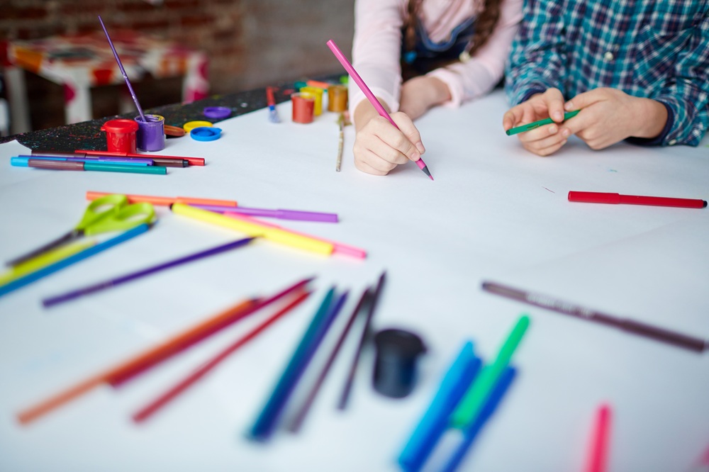 子どもが色鉛筆で画用紙に絵を描く