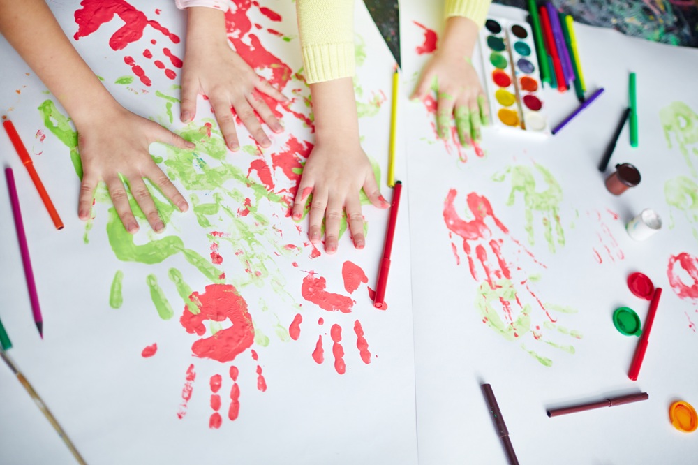 子どもが絵具を手に塗り手跡をつける