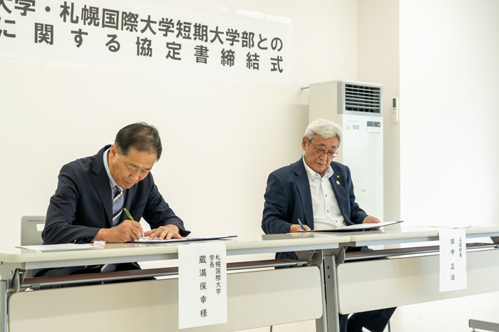 協定書へ調印する蔵満学長、田中村長